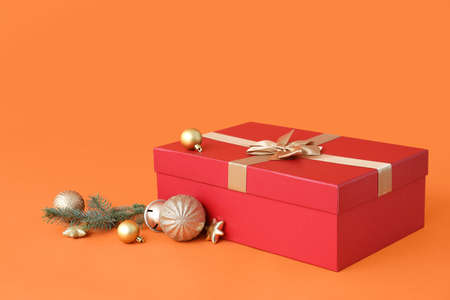 Christmas gift box with balls and fir branches on color backgroundの写真素材