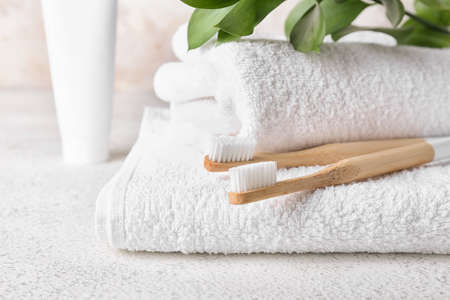 Soft towels and wooden toothbrushes on light table, closeupの写真素材