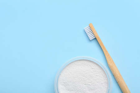 Wooden toothbrush and powder on blue background, closeup
