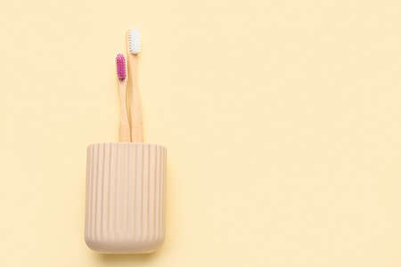 Holder with different wooden toothbrushes on color background