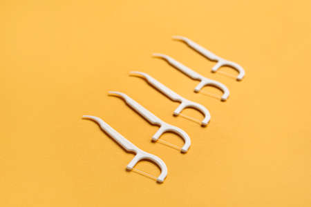 Floss toothpicks on orange backgroundの写真素材