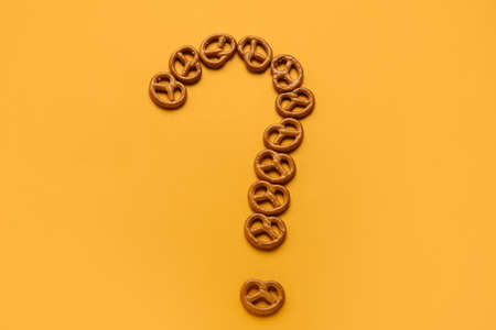 Question mark made of mini pretzels on orange backgroundの写真素材