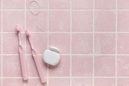 Dental floss with toothbrushes on pink tile backgroundの写真素材