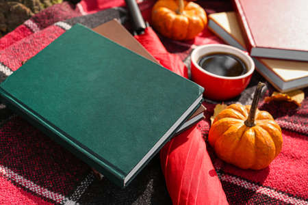 Books, umbrella, pumpkins and cup of coffee on plaid, closeupの写真素材