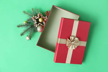 Christmas gift box with balls and fir branches on green background