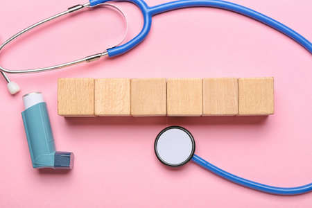 Asthma inhaler, stethoscope and blank wooden cubes on color backgroundの写真素材
