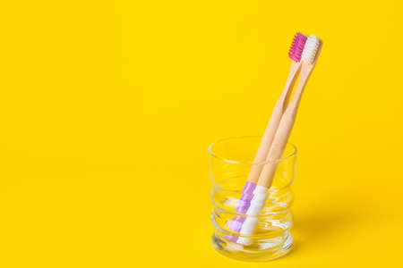 Glass with wooden toothbrushes on yellow backgroundの写真素材