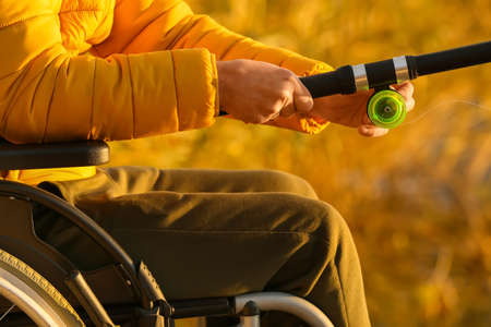 Man in wheelchair fishing on river