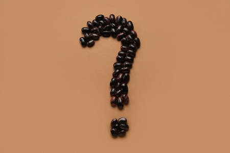 Question mark made of black beans on brown background