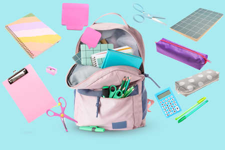 School backpack and stationery on light blue background