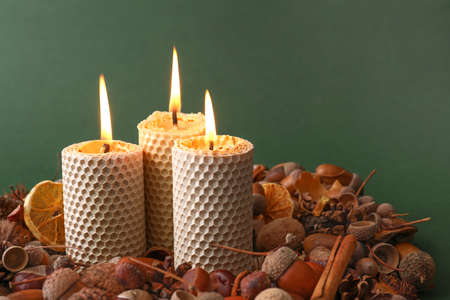 Beautiful burning candles and autumn decor on color backgroundの写真素材
