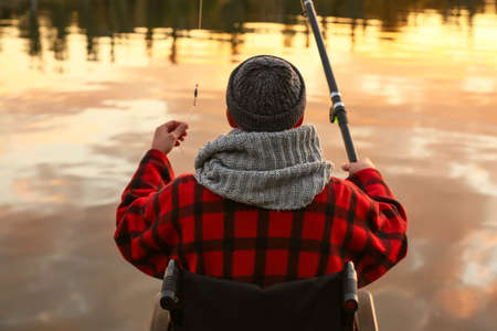 Man in wheelchair fishing on riverの写真素材