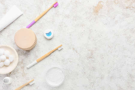 Bamboo toothbrushes with powder, floss and cotton balls on grunge background