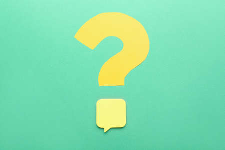Question mark made of yellow paper with sticky note on green backgroundの写真素材