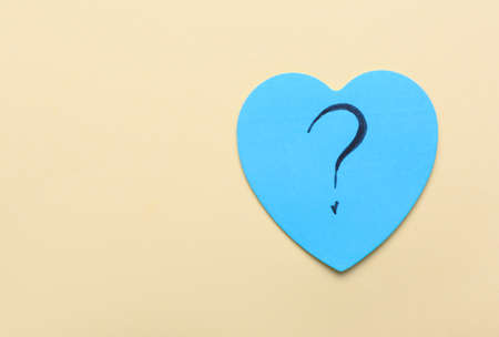Heart shaped sticky note with question mark on beige backgroundの写真素材