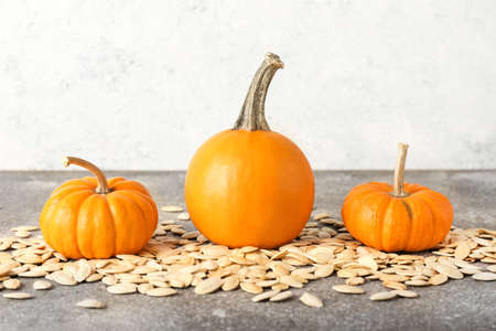 Pile of natural pumpkin seeds and fresh vegetables on tableの写真素材