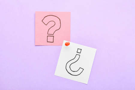 Sticky notes with question marks and pin on lilac backgroundの写真素材