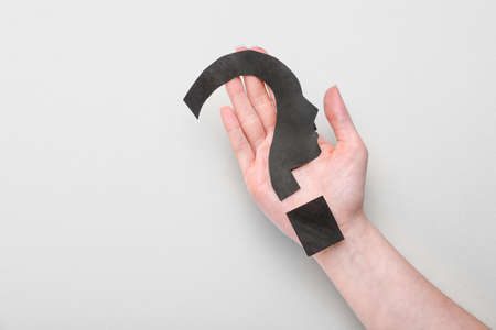 Woman holding question mark made of black paper on light background