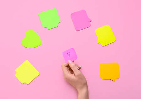 Woman holding sticky note with question mark on pink backgroundの写真素材
