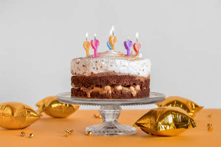 Stand with tasty birthday cake and balloons on table