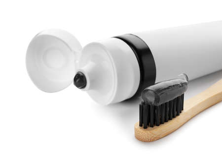 Tube with black tooth paste and brush on white background