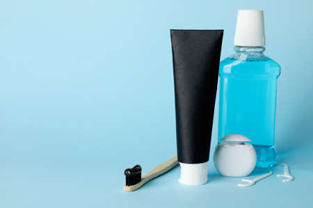 Tube of black toothpaste, brush, rinse and floss on blue backgroundの写真素材
