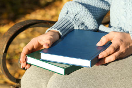 Woman sitting on bench with books, closeup