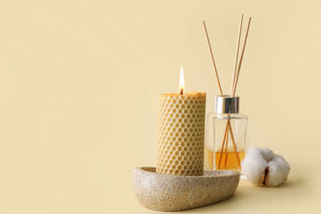 Composition with glowing candle on yellow background