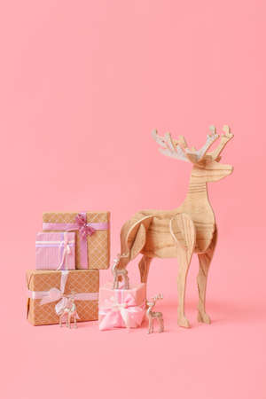 Wooden reindeer with Christmas presents on pink backgroundの写真素材