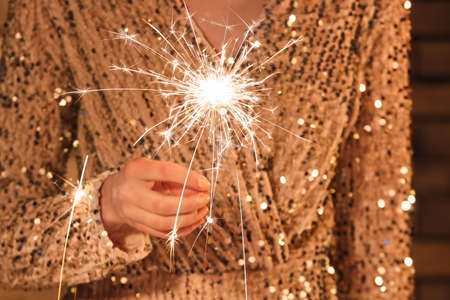 Woman holding shiny Christmas sparkler, closeupの写真素材