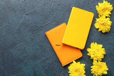 Yellow chrysanthemum flowers and notebooks on dark backgroundの写真素材