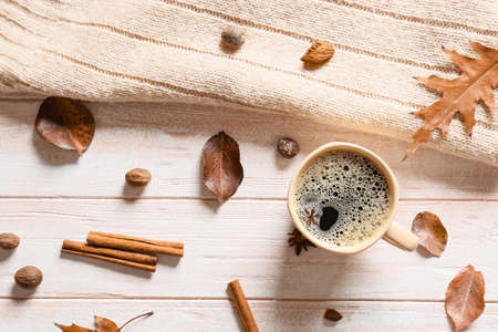 Composition with cup of coffee, spices and autumn leaves on light wooden backgroundの写真素材