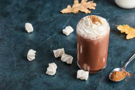Glass of tasty coffee with cinnamon on black background