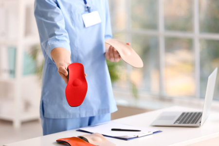 Female nurse holding different orthopedic insoles in clinicの写真素材