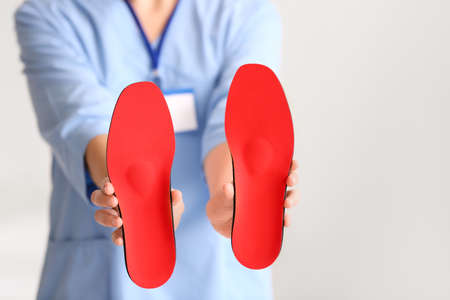 Female nurse holding red orthopedic insoles in clinic, closeupの写真素材