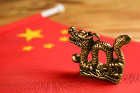 Figurine of dragon and Chinese flag on wooden backgroundの写真素材