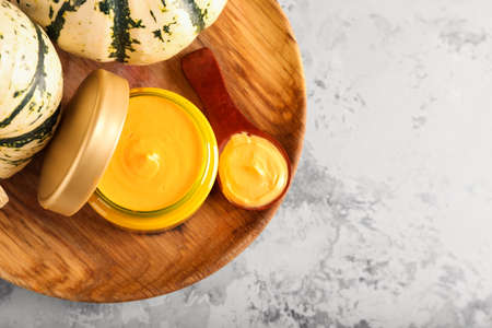 Wooden plate with jar of natural mask and pumpkins on grunge background, closeupの写真素材