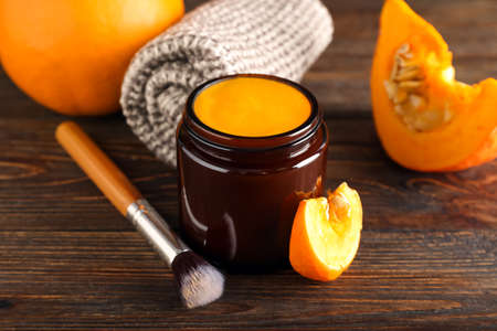 Jar of natural pumpkin mask and makeup brush on wooden backgroundの写真素材