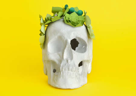 Human skull with handmade paper flowers on yellow backgroundの写真素材