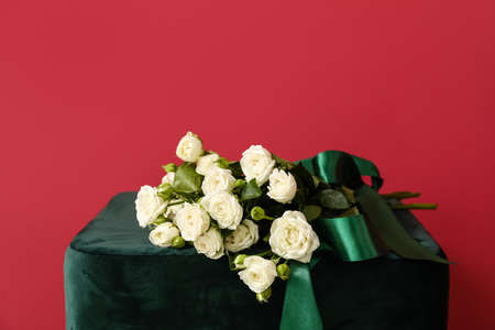 Bouquet of beautiful roses on pouf near red wallの写真素材