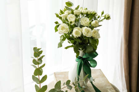 Vase with bouquet of beautiful roses on table in roomの写真素材