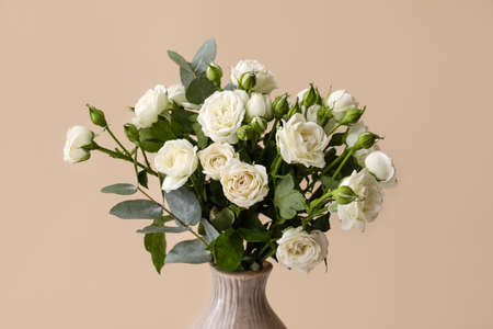 Vase with bouquet of beautiful roses on beige backgroundの写真素材