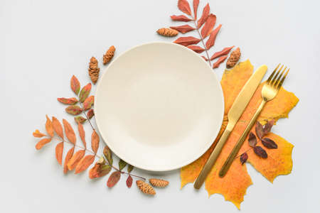 Composition with table setting and autumn leaves on light backgroundの写真素材