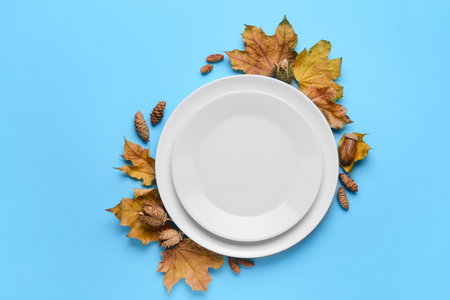 Composition with table setting and autumn leaves on blue backgroundの写真素材