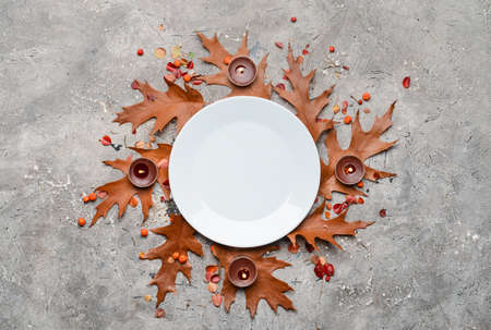 Composition with table setting, autumn leaves and candles on gray backgroundの写真素材