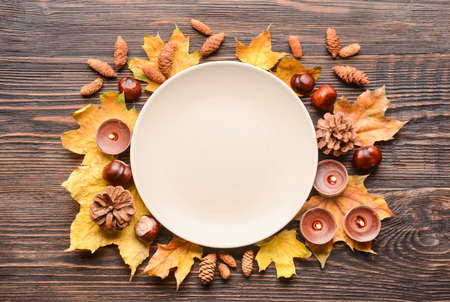 Composition with table setting, autumn leaves and candles on wooden backgroundの写真素材