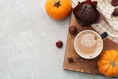 Cup of tasty pumpkin coffee and muffin on light backgroundの写真素材