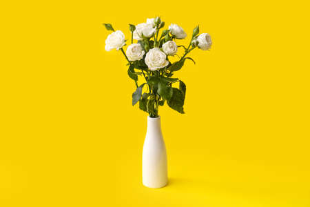 Vase with bouquet of beautiful roses on yellow backgroundの写真素材