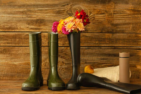 Rubber boots, flowers and flask on wooden backgroundの写真素材