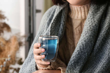 Woman with cup of tasty blue tea at home, closeupの写真素材